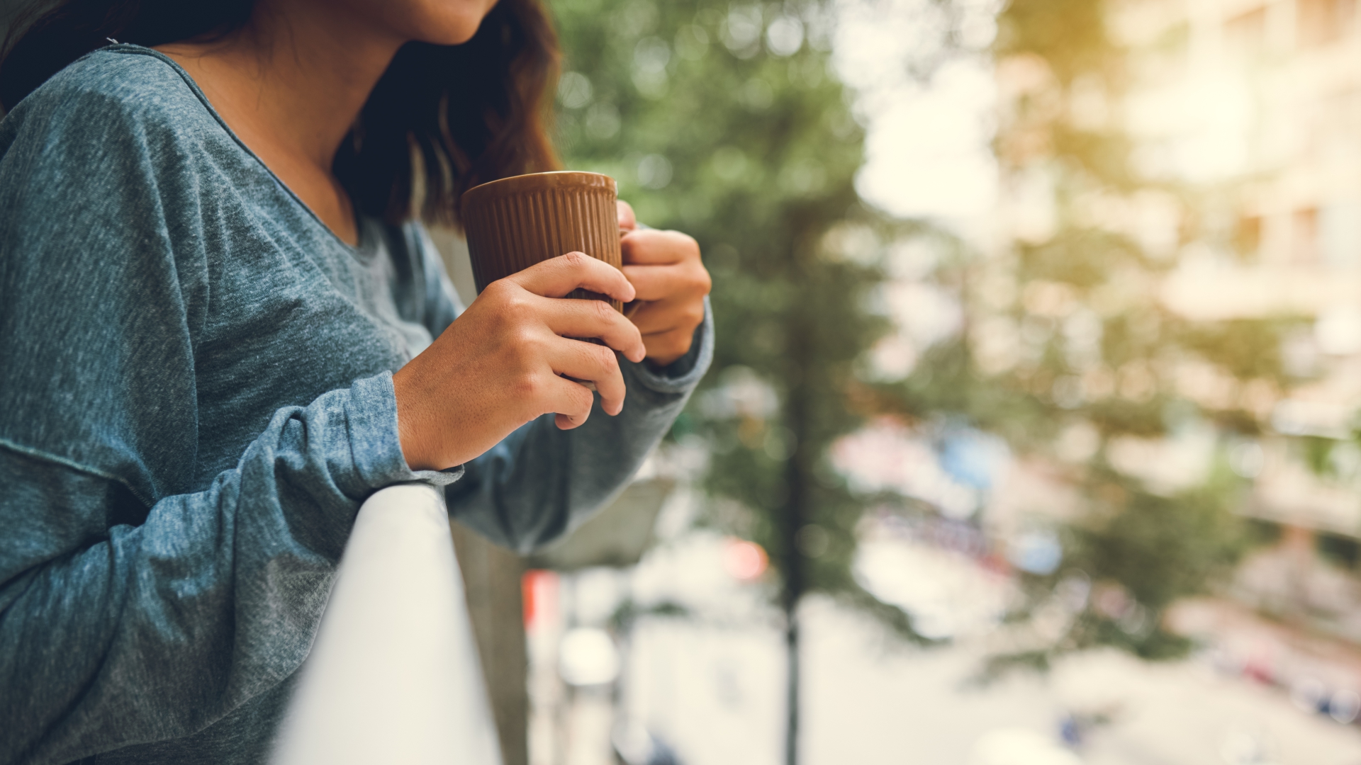 Bild zeigt den Oberkörper einer Frau, die eine Tasse in der Hand hält